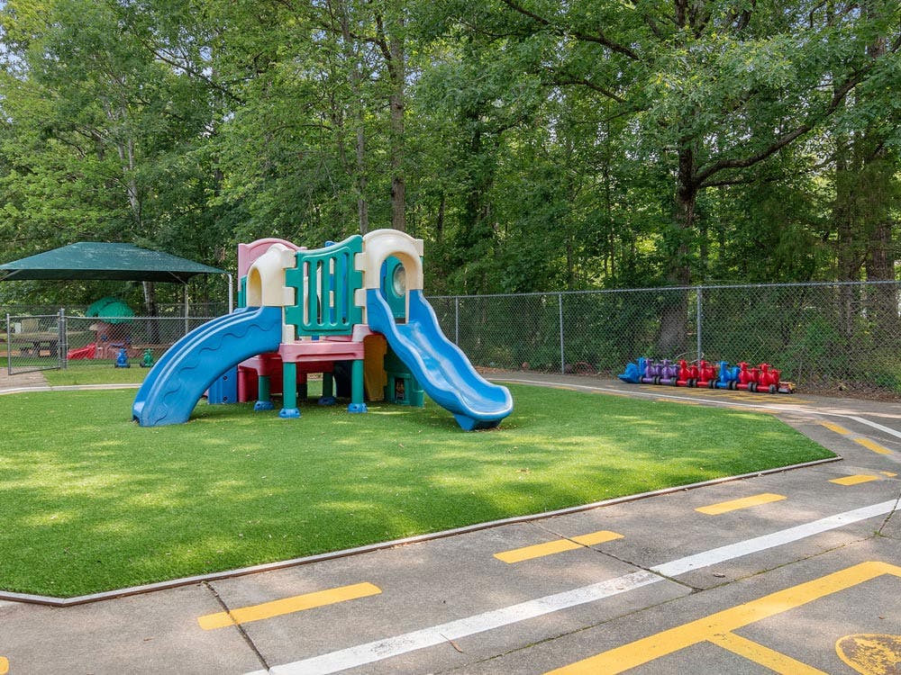 Colorful playground structure on artificial turf with toy vehicles nearby