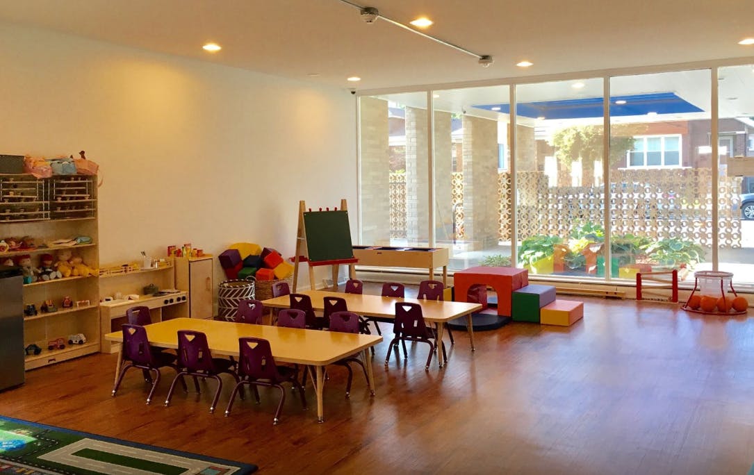 Classroom with small tables and chairs, shelves, and a large window