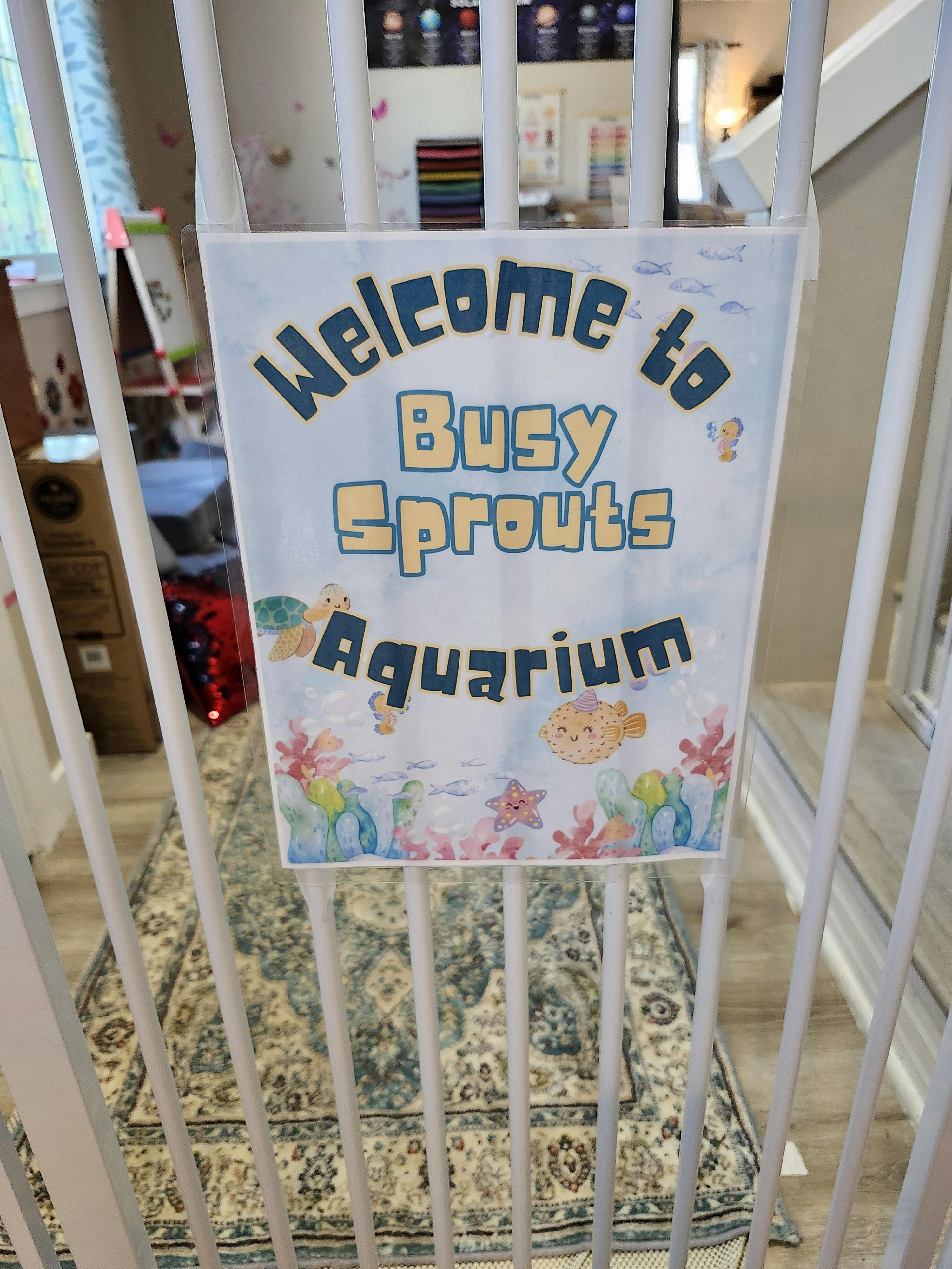 Sign reading Welcome to Busy Sprouts Aquarium attached to a white safety gate