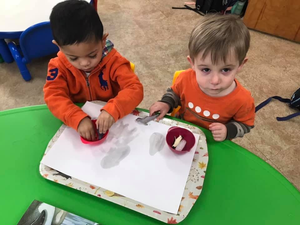 Two children at a table with paper and art supplies