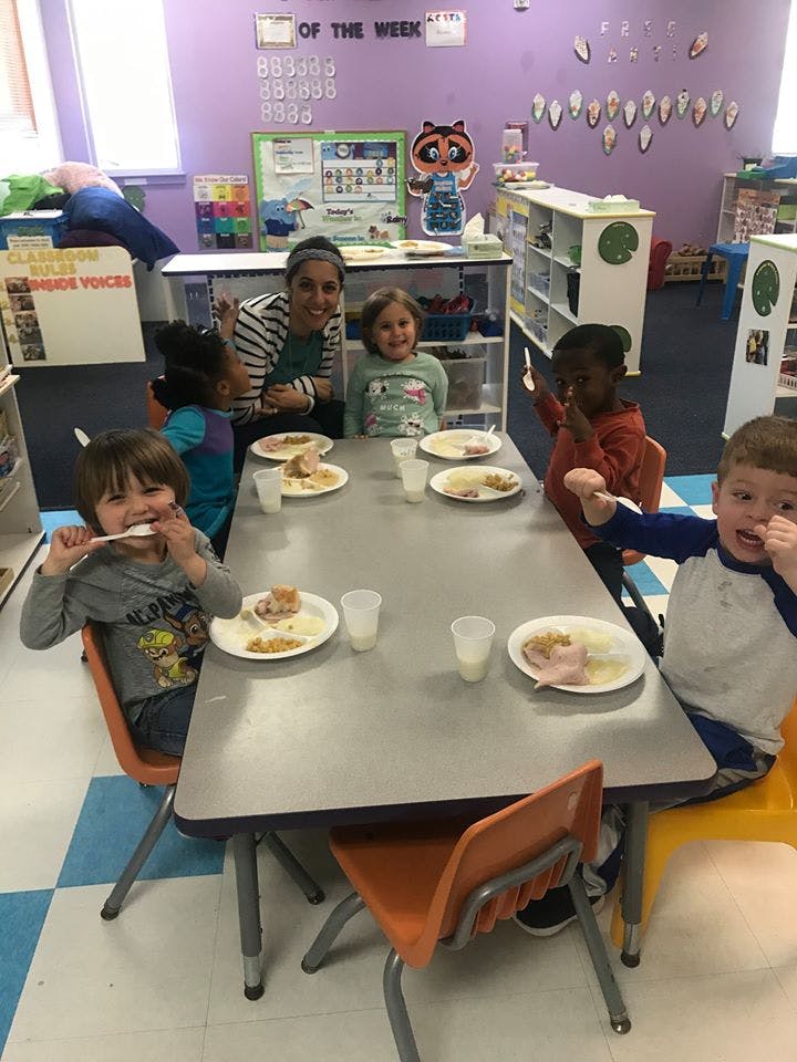 Adult and children eating at a table in a classroom