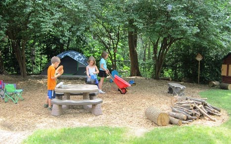 Children playing outdoors near a picnic table and tent