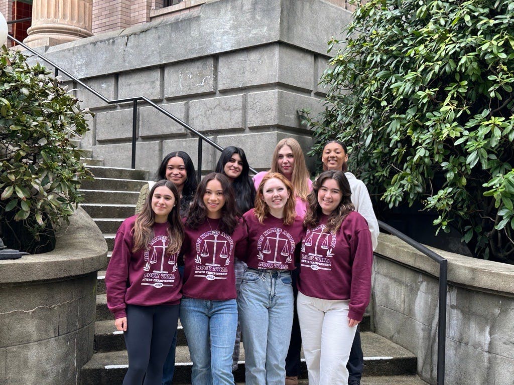 Group of seven people in "Mock Trial" sweatshirts on stone steps