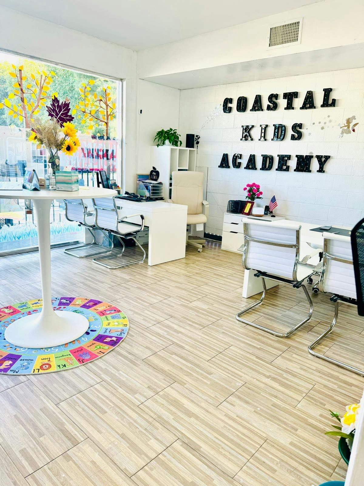 Office interior with "Coastal Kids Academy" on wall, desks, and chairs