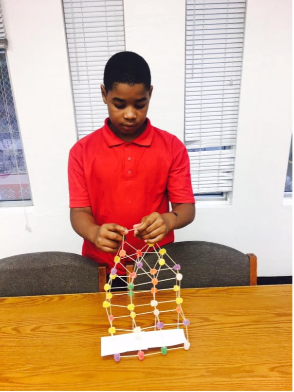 Child building a structure with toothpicks and gumdrops
