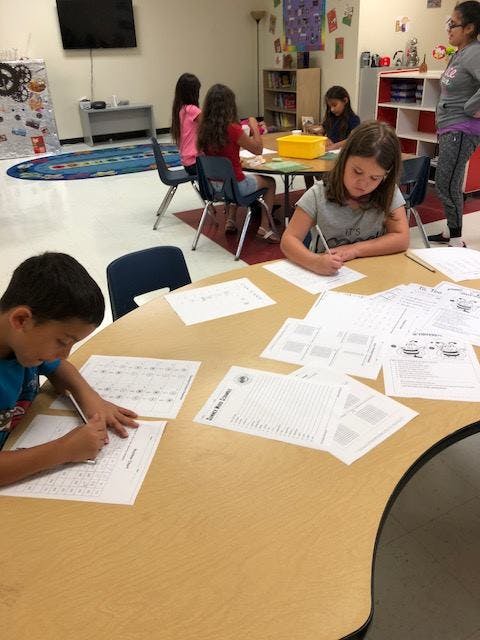 Children writing at tables in a classroom