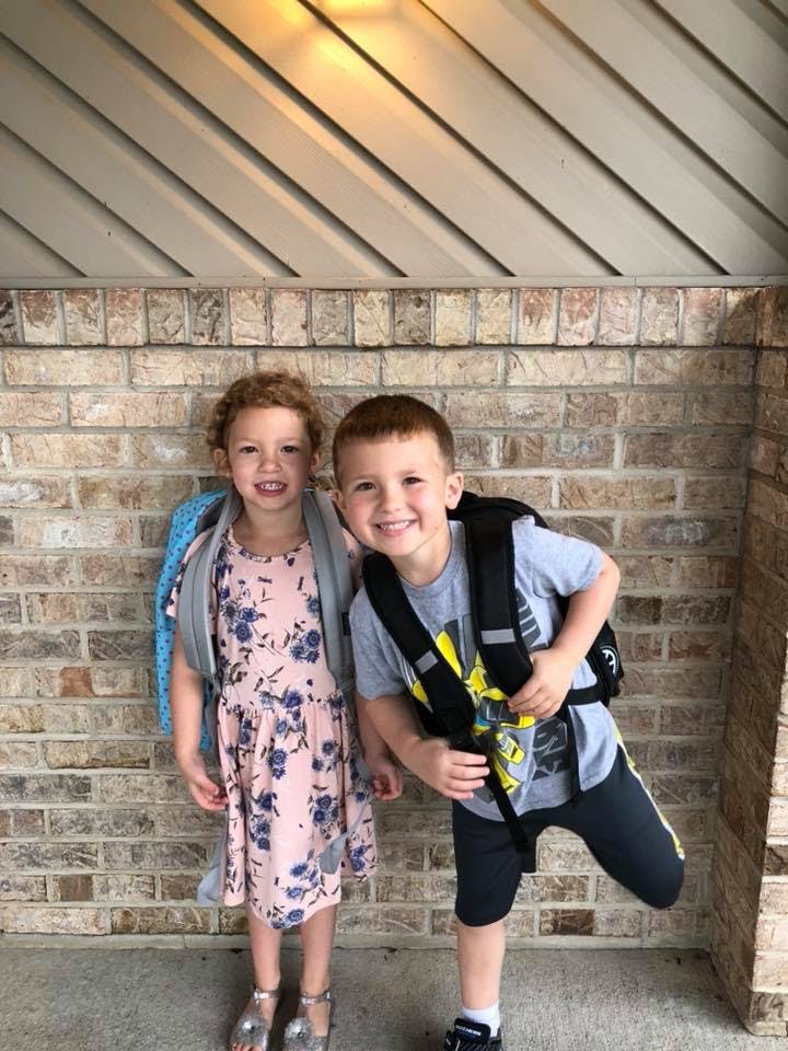 Two children standing in front of a brick wall