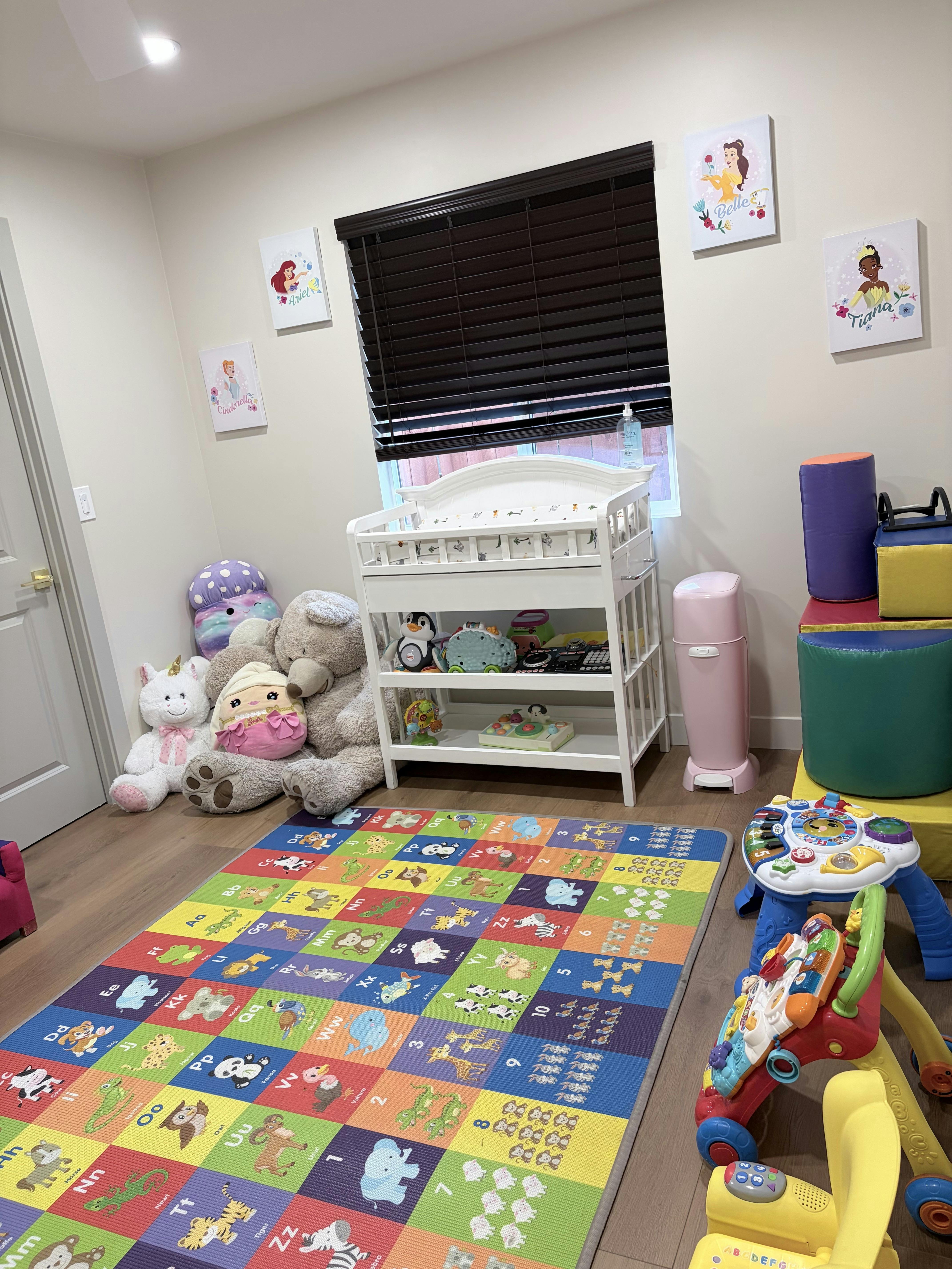 Colorful alphabet play mat in a child nursery with toys and a changing table