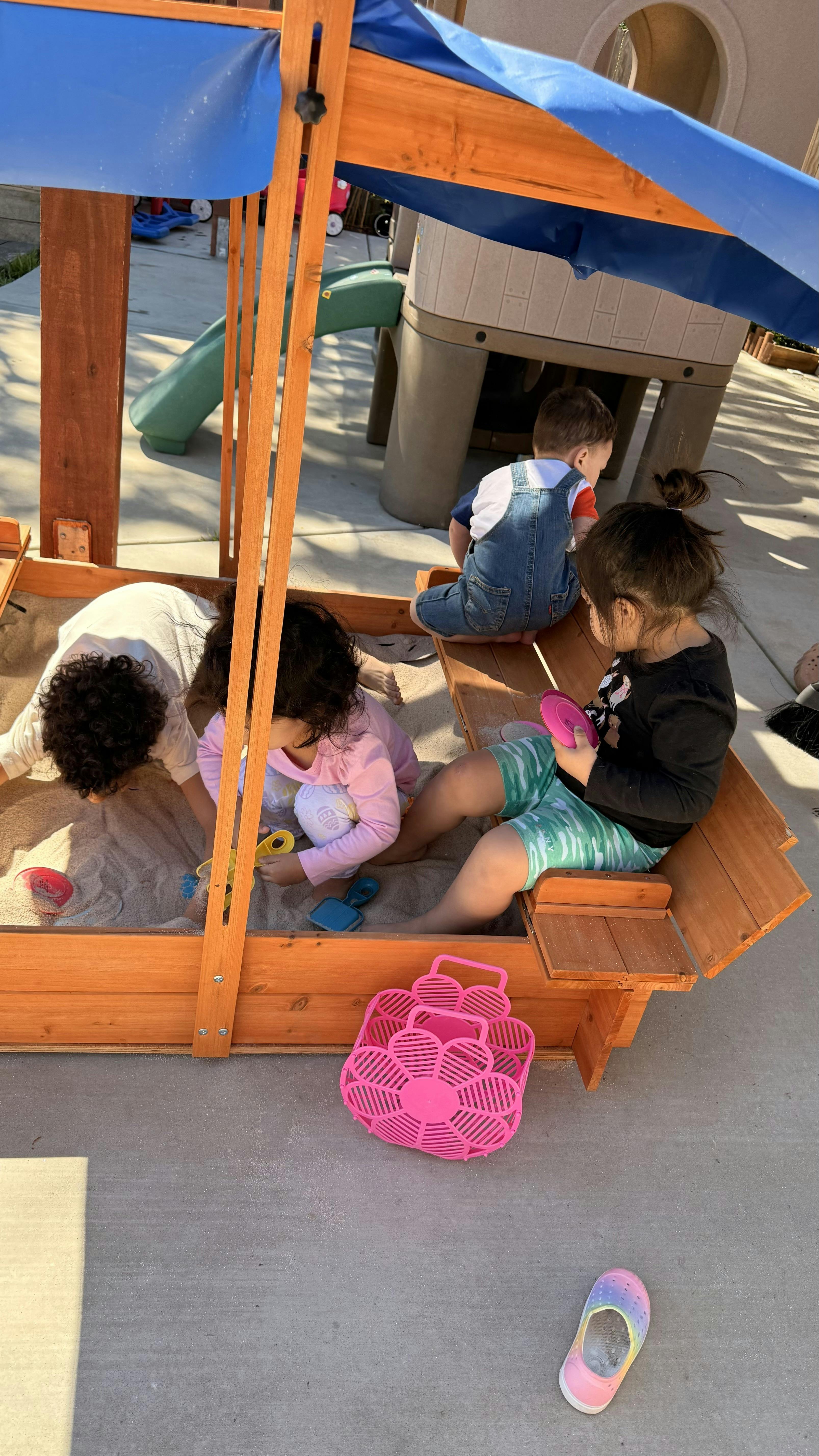 Children playing in a wooden sandbox