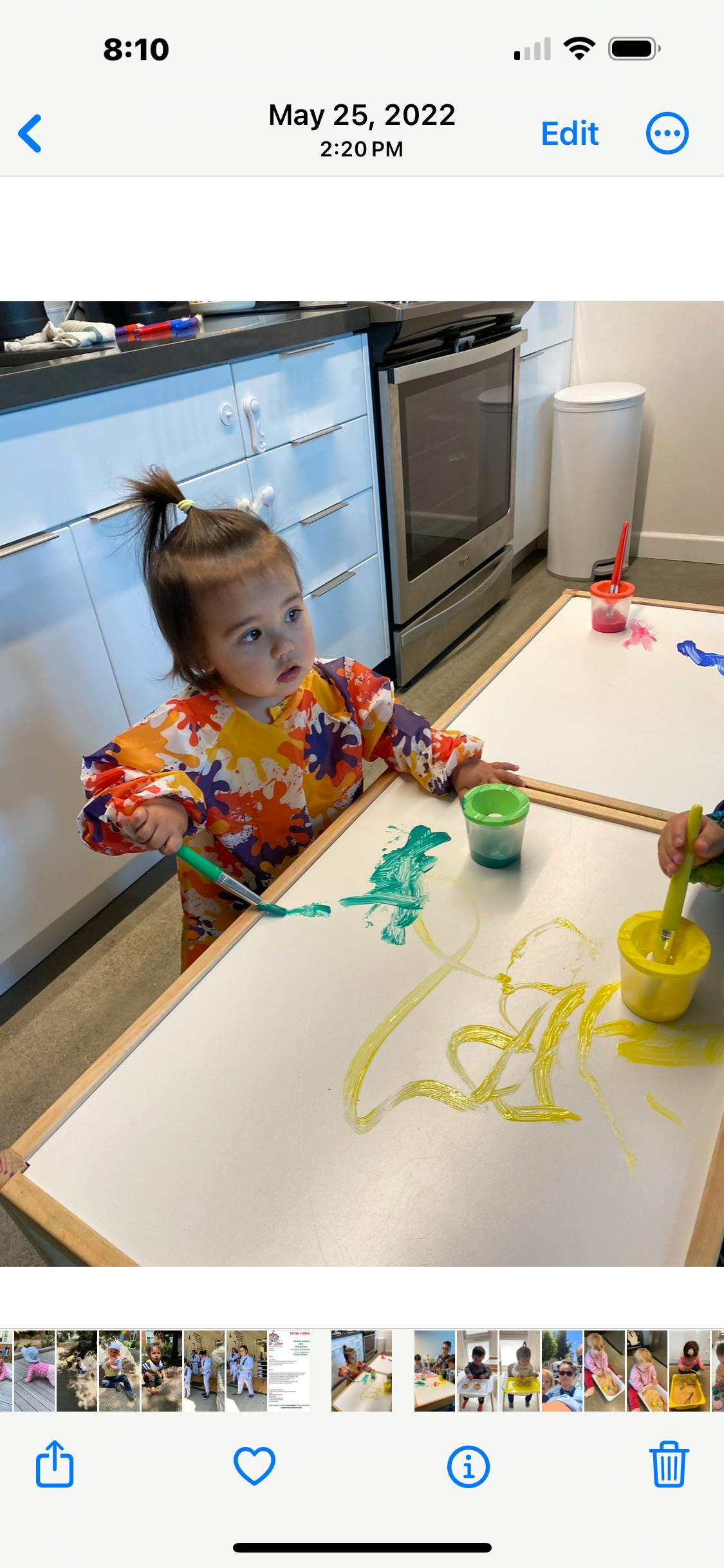 Child painting on a white board with green and yellow paint