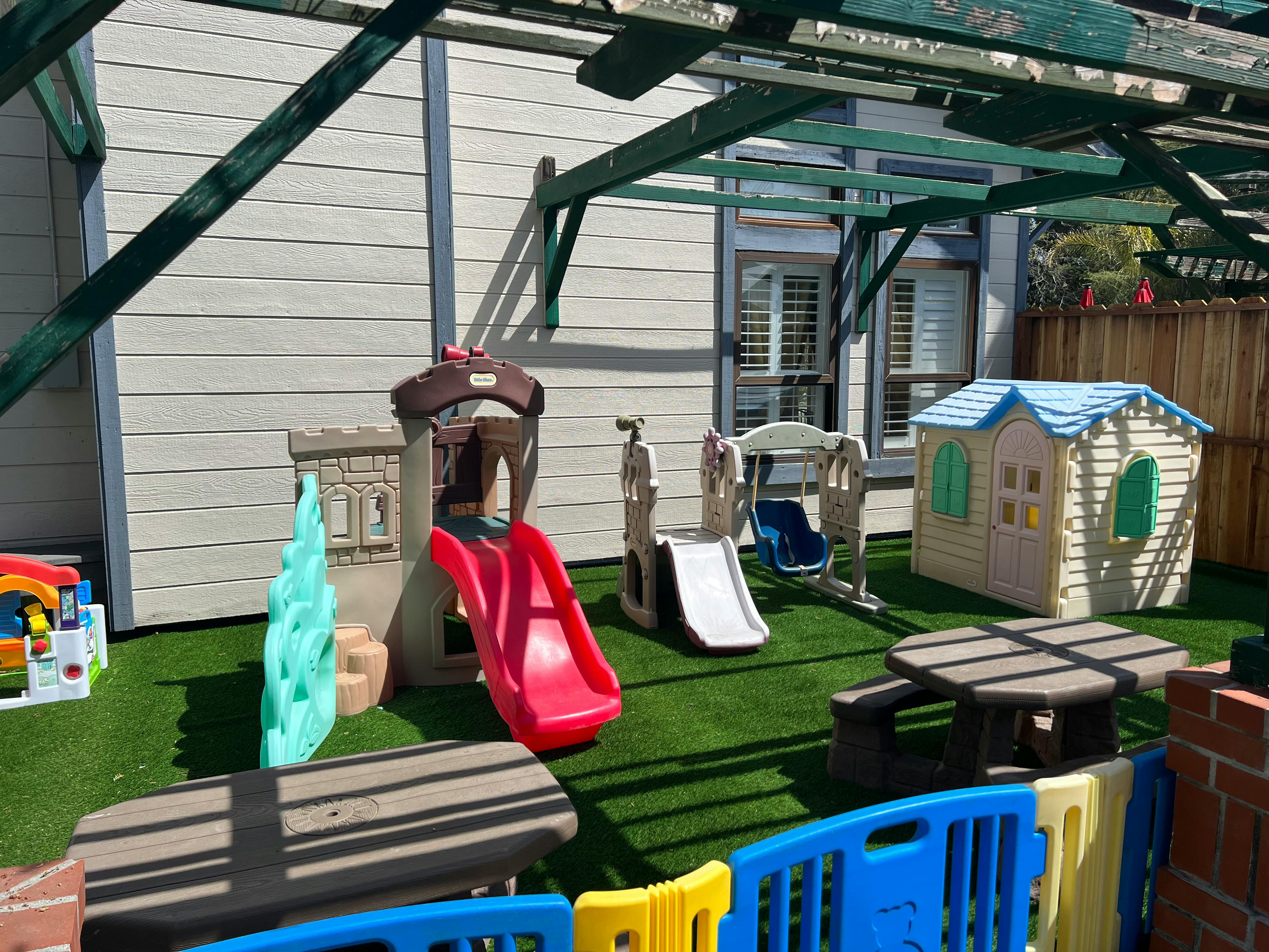 Outdoor play area with slides, swings, a playhouse, and a picnic table