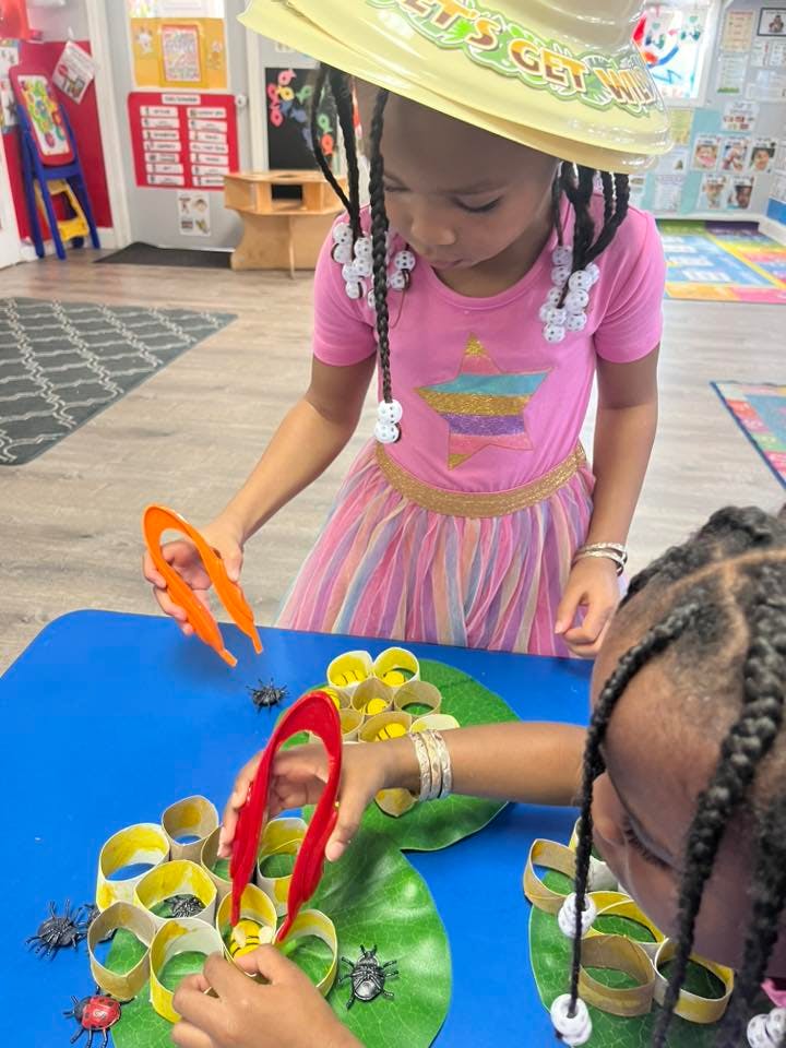 Child in a classroom using tongs to pick up toy insects