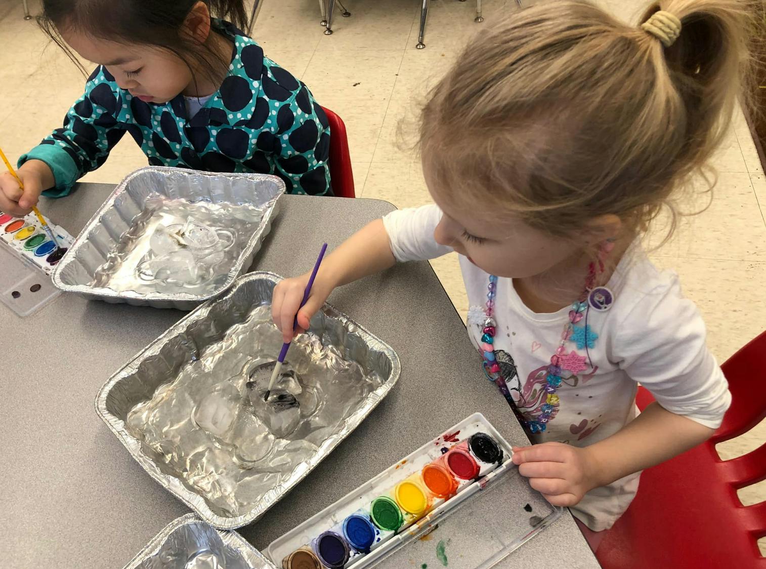 Two children painting with watercolors at a table