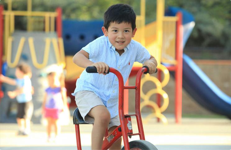 Child riding a tricycle on a playground
