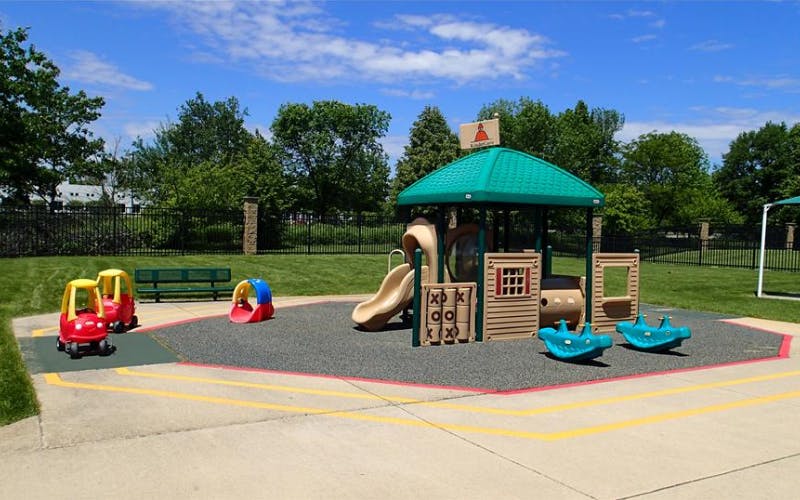 Playground with climbing structure, slide, and two ride-on toys