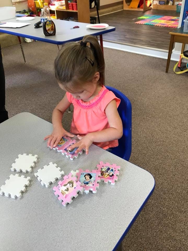 Child playing with puzzle pieces at a table