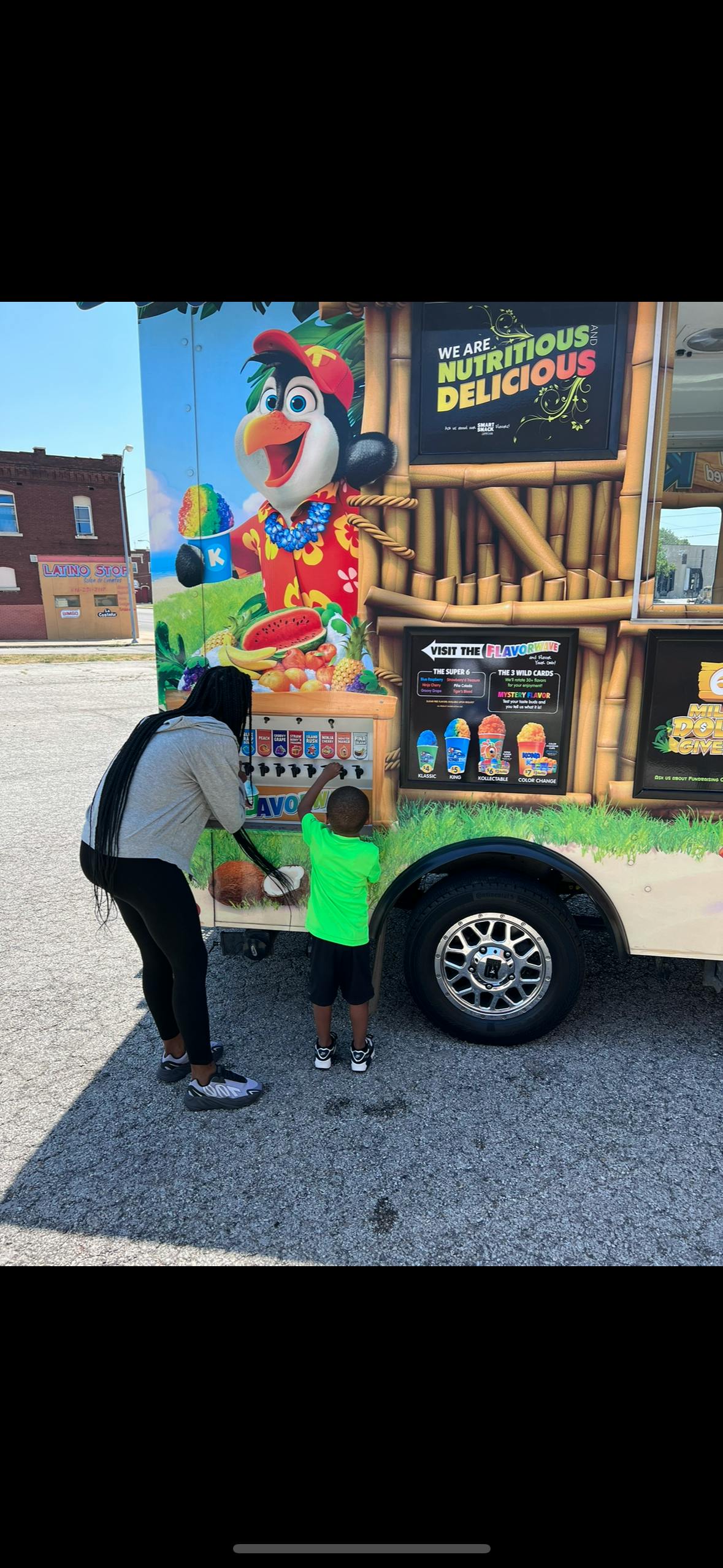Person and child at a food truck with a penguin mascot