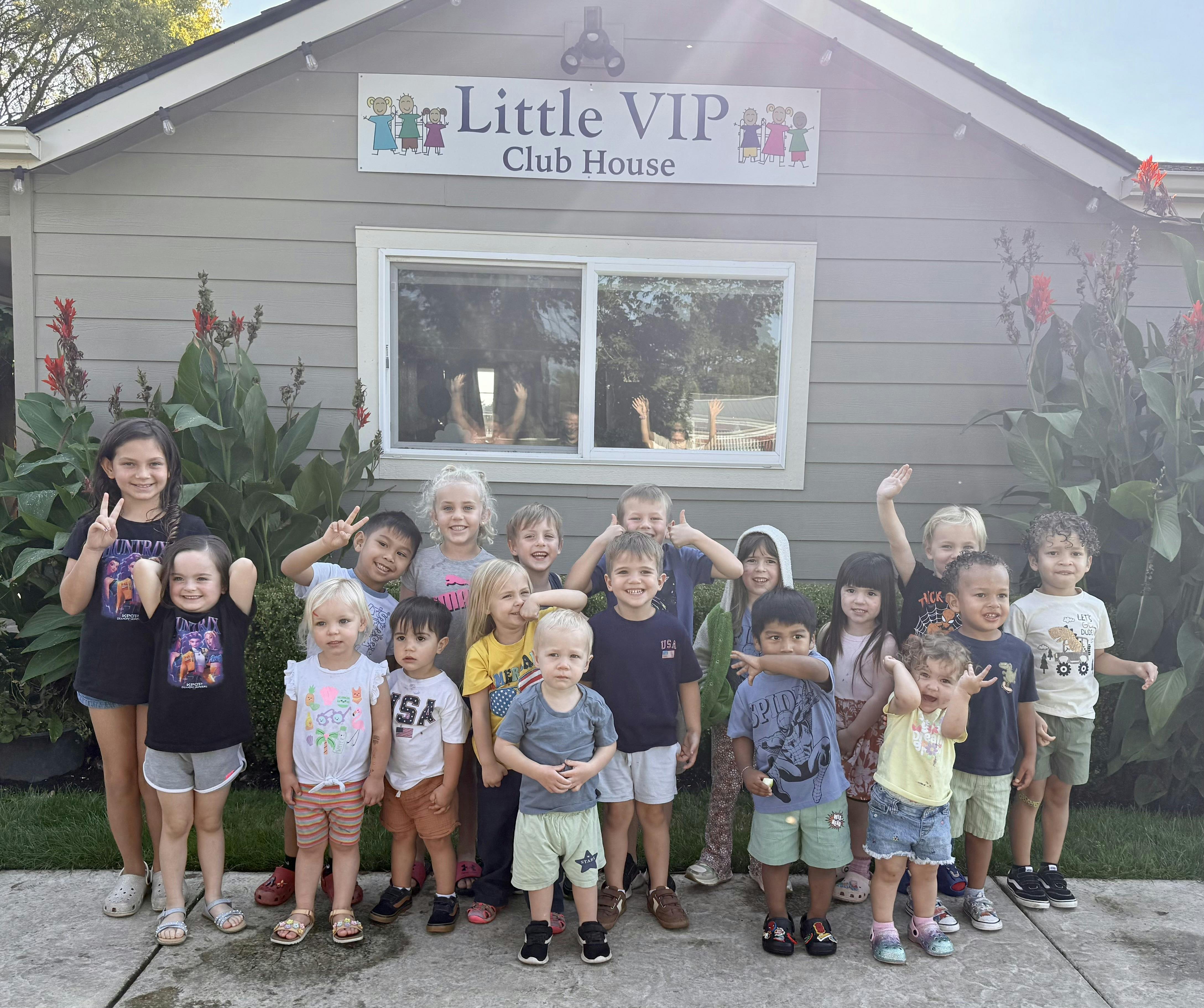 Group of children standing in front of Little VIP Club House sign