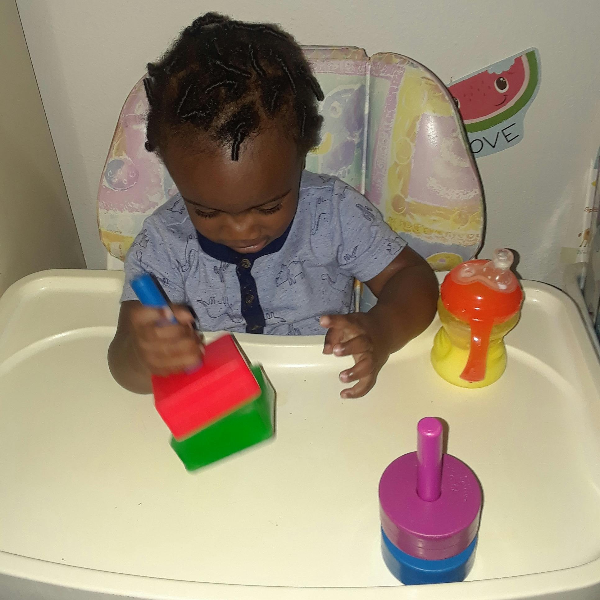 Child in high chair playing with stacking blocks
