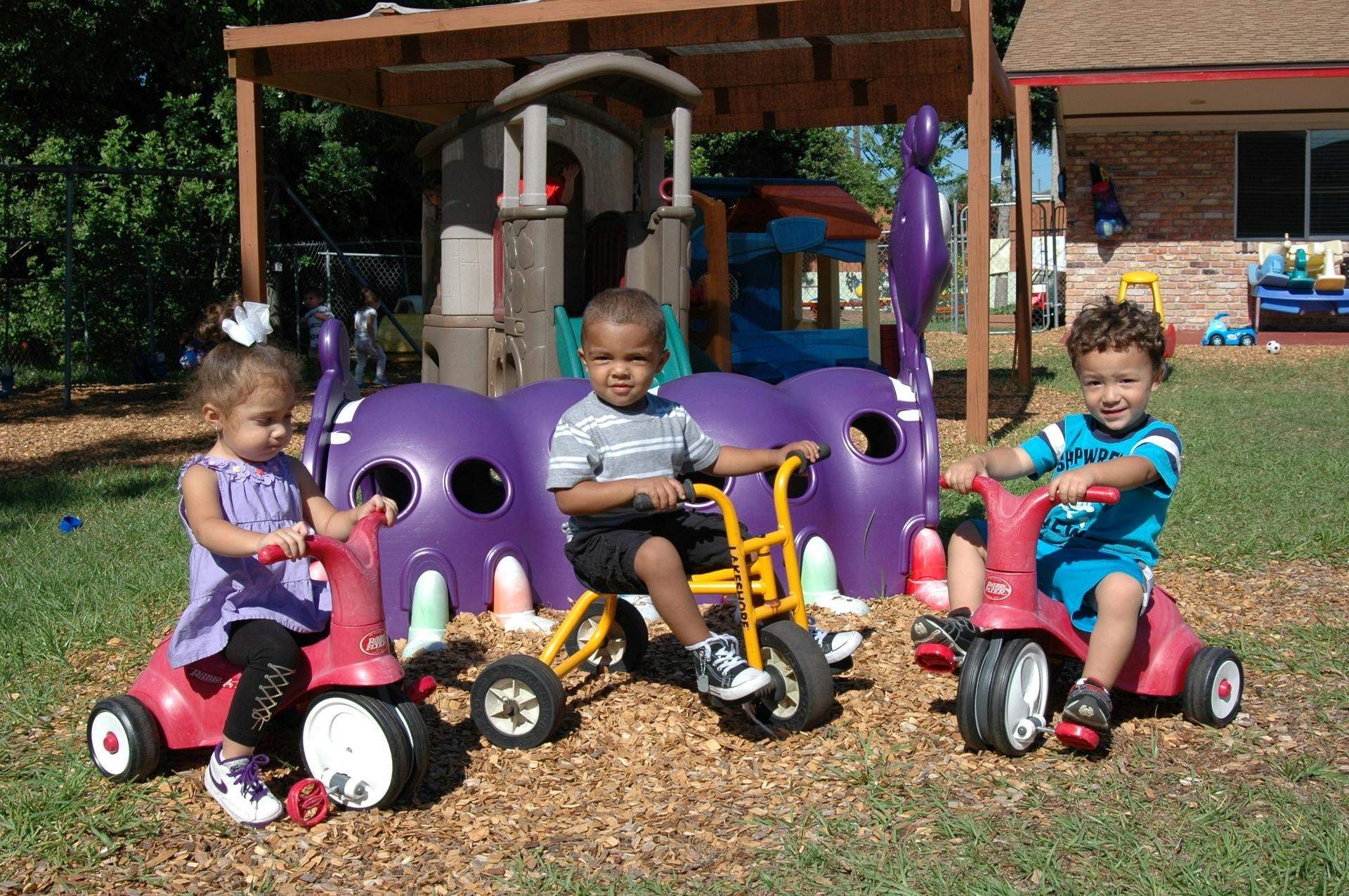 Three children on tricycles on a playground