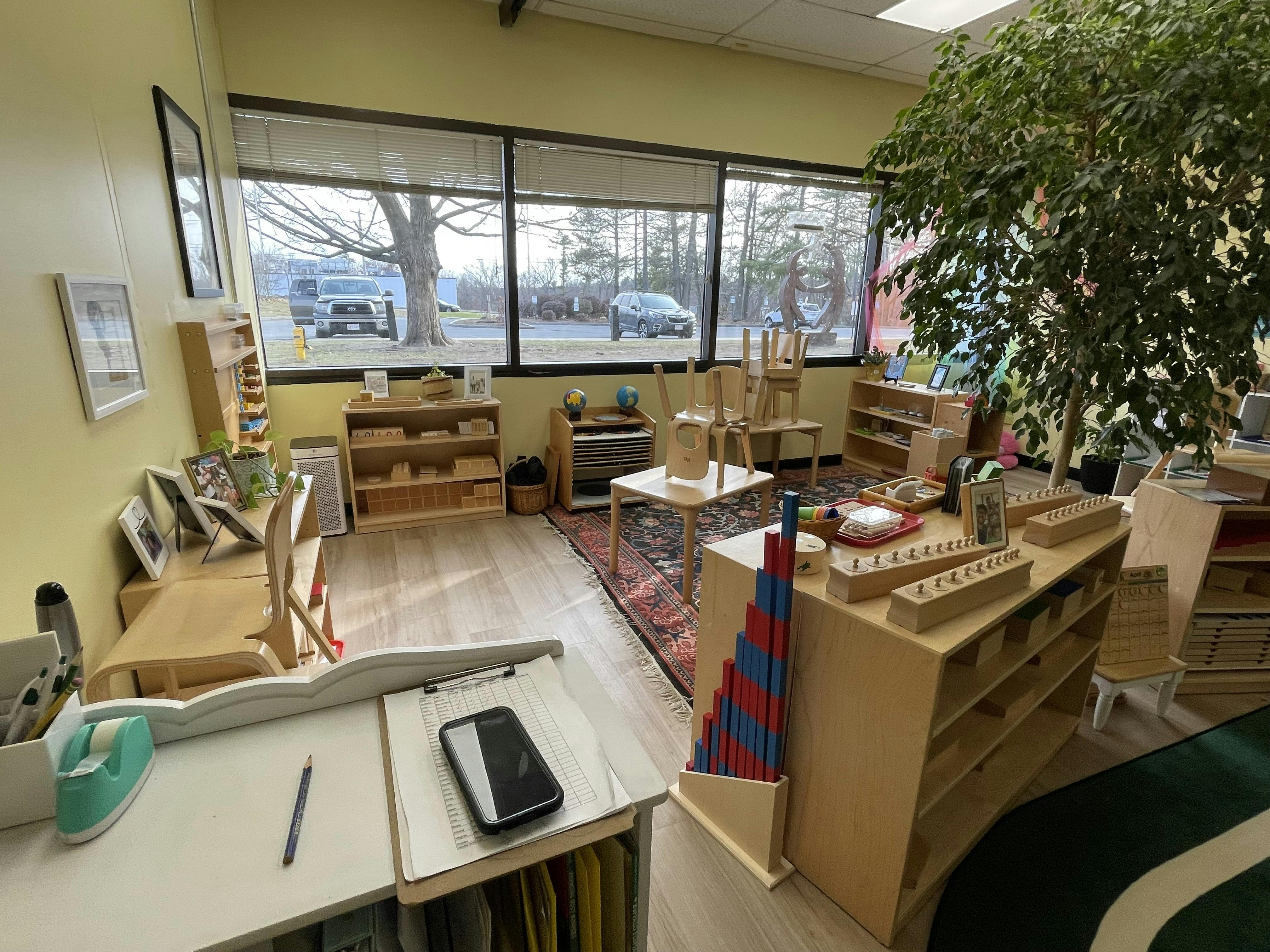 Classroom with wooden furniture and learning materials, large windows