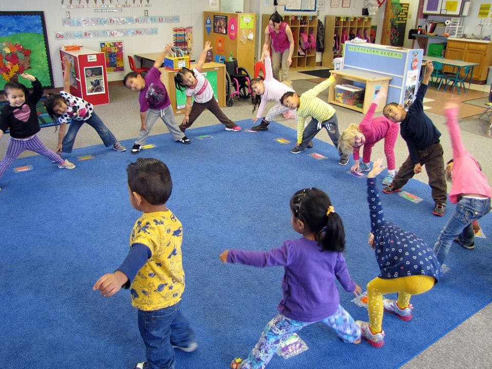 Children in a classroom doing stretches in-place stretches