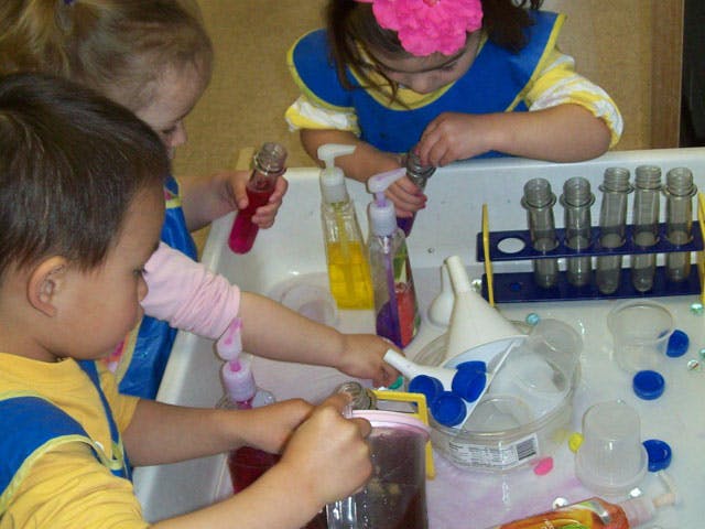 Children playing with water and science tools in a sensory bin