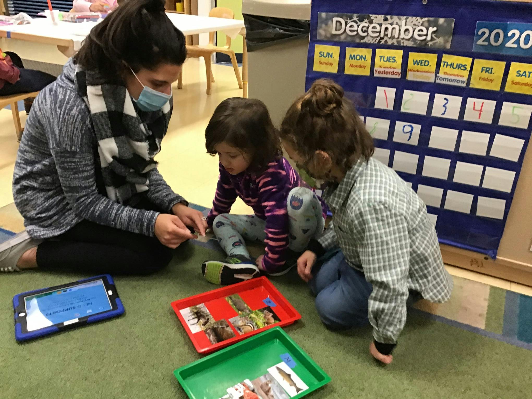 Person in mask with two children looking at items on the floor