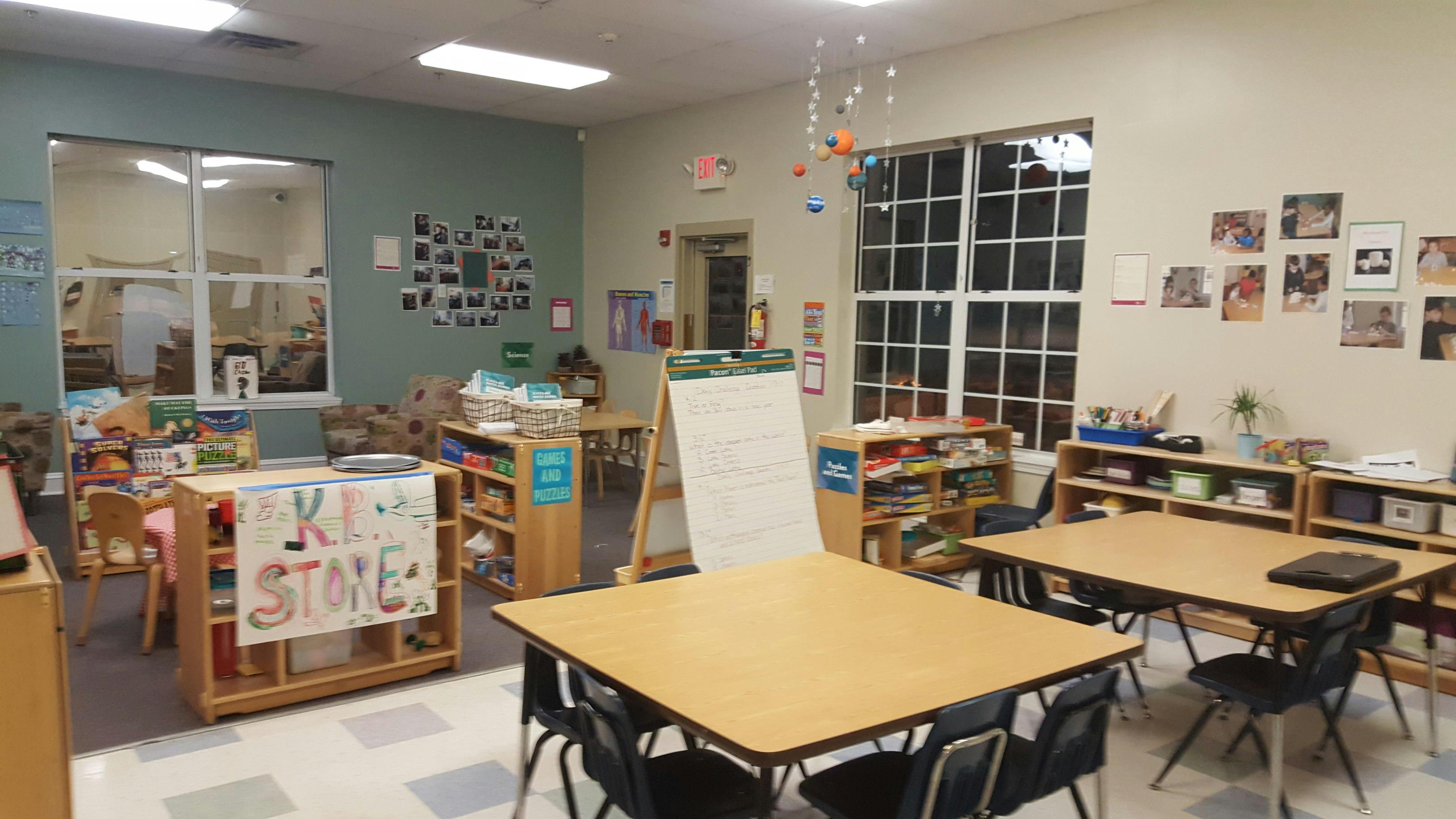 Classroom with tables, chairs, shelving units, and a window