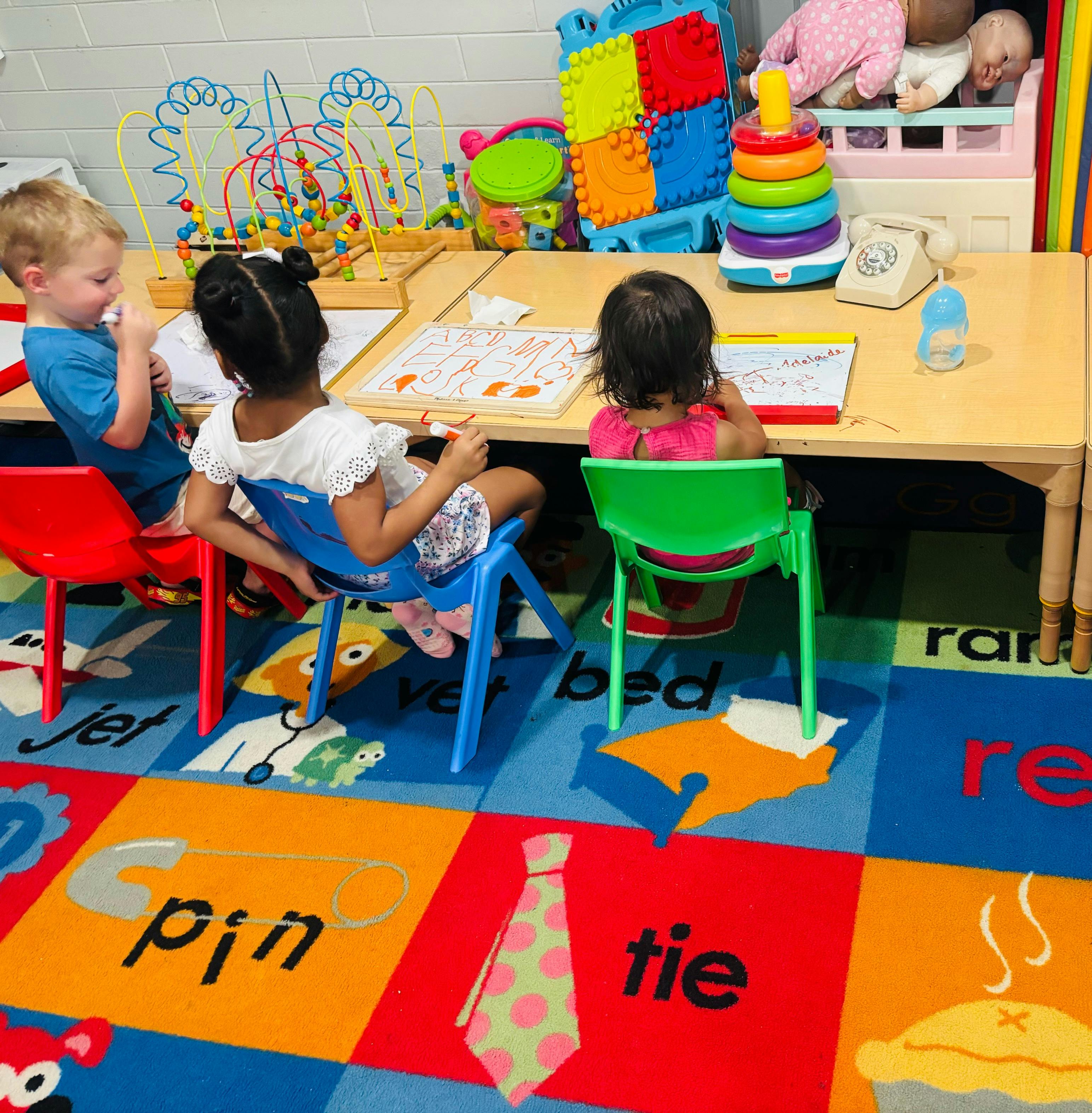 Three children sitting at a table in a classroom