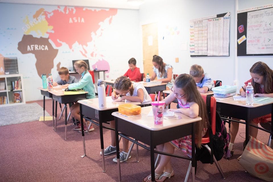 Children sitting at desks in a classroom, writing