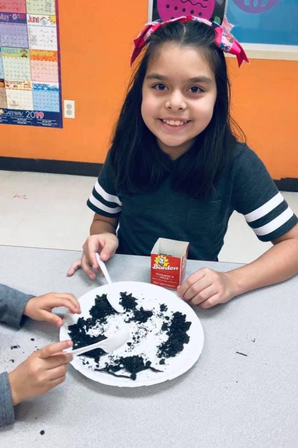 Child and person making a craft with black paper and white glue