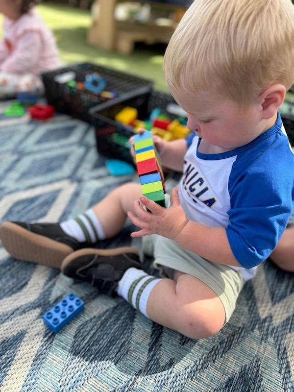Child sitting on a rug and playing with plastic building blocks