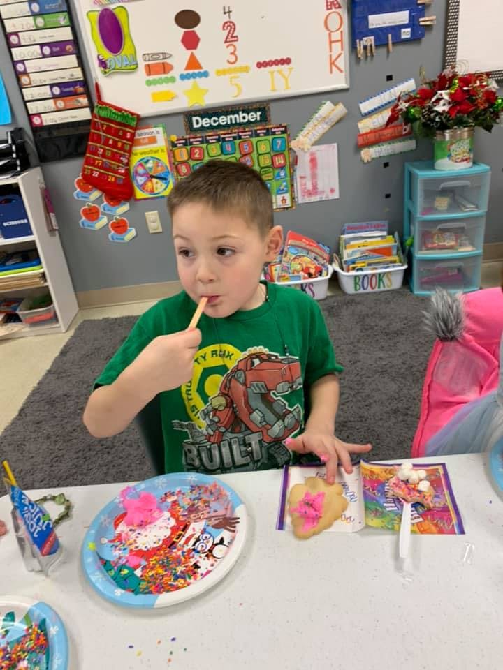 Child decorating a cookie with sprinkles