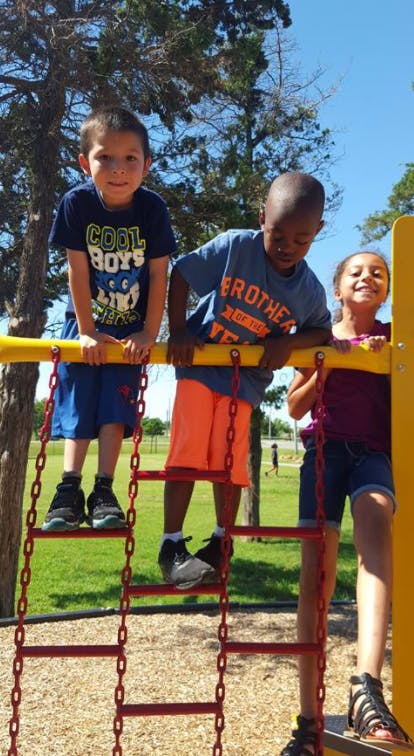 Three children on a playground climbing structure