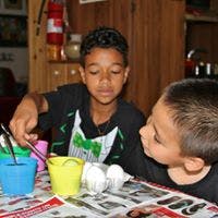 Two children painting eggs at a table