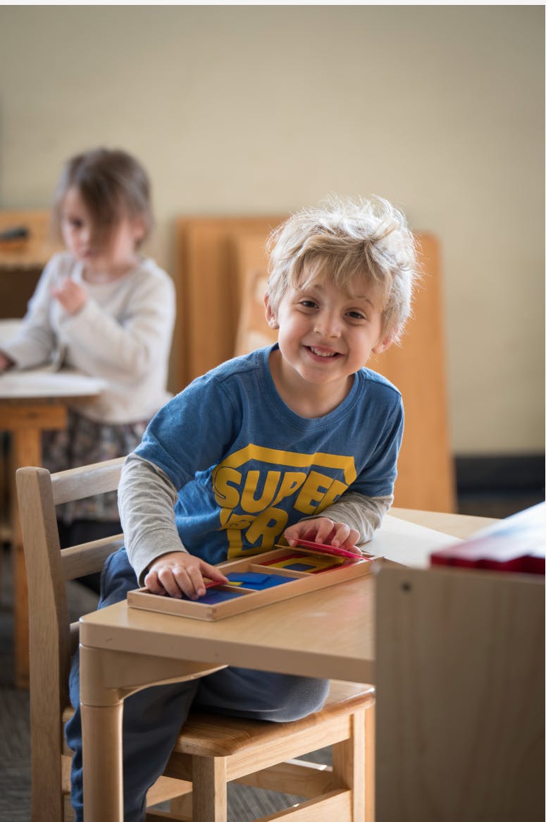 Child sitting at a table, playing with a wooden puzzle