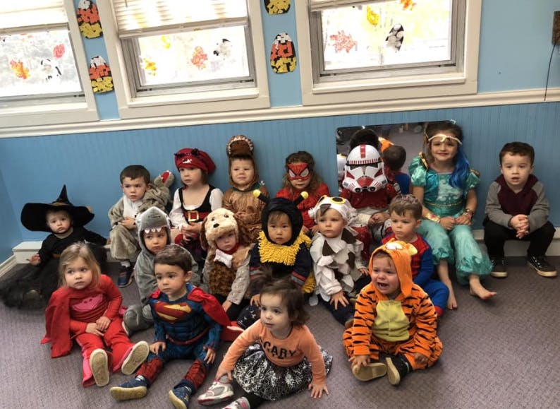 Group of children in various costumes sitting on the floor