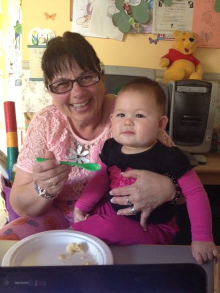 Person holding a child and a green spoon