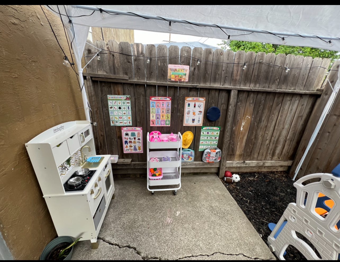 Outdoor play area with toy kitchen and storage cart