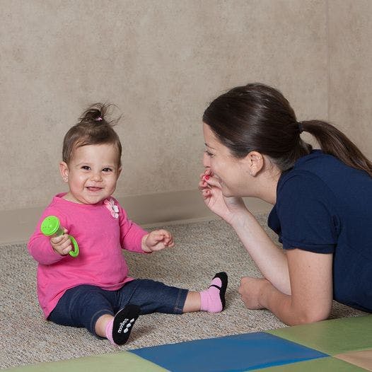 Adult and child on floor, child holding a green toy