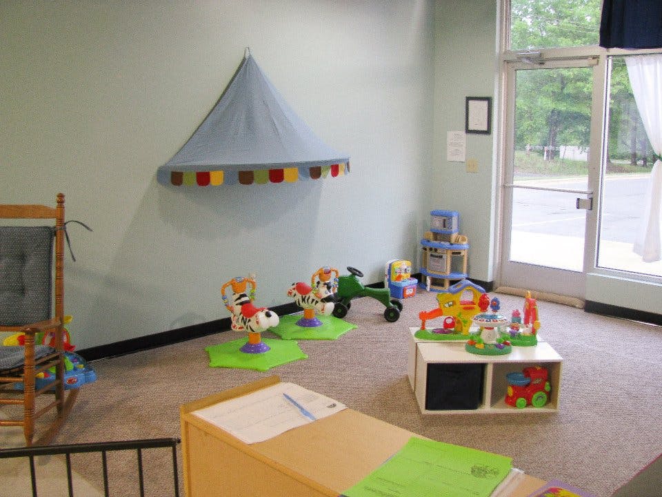 Playroom with toys, a rocking chair, and a canopy on-wall canopy
