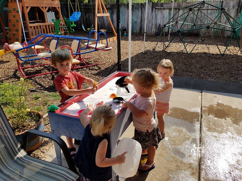 Children playing at a sand and water table outdoors