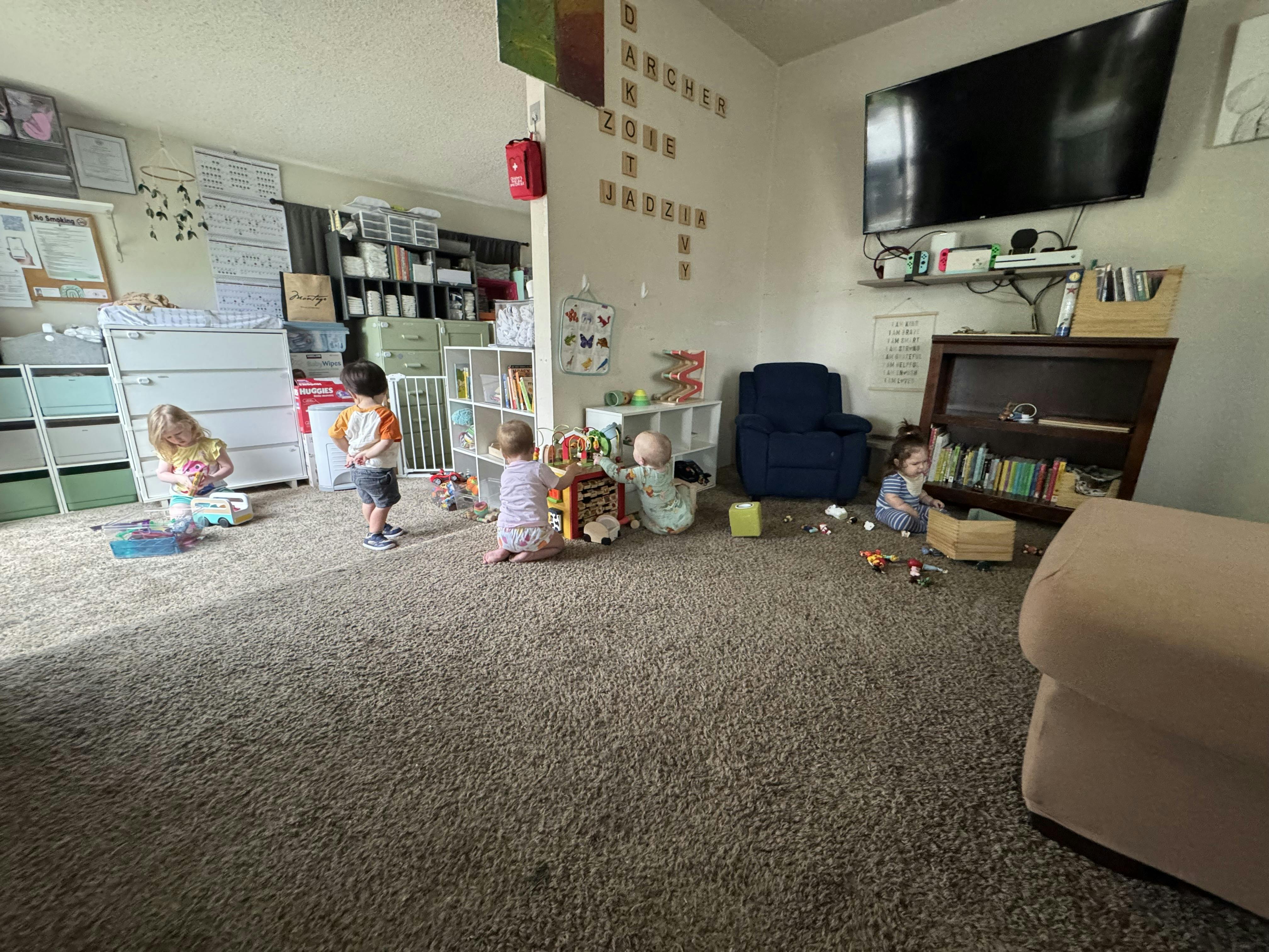 Five children playing with toys on a carpeted floor in a living room