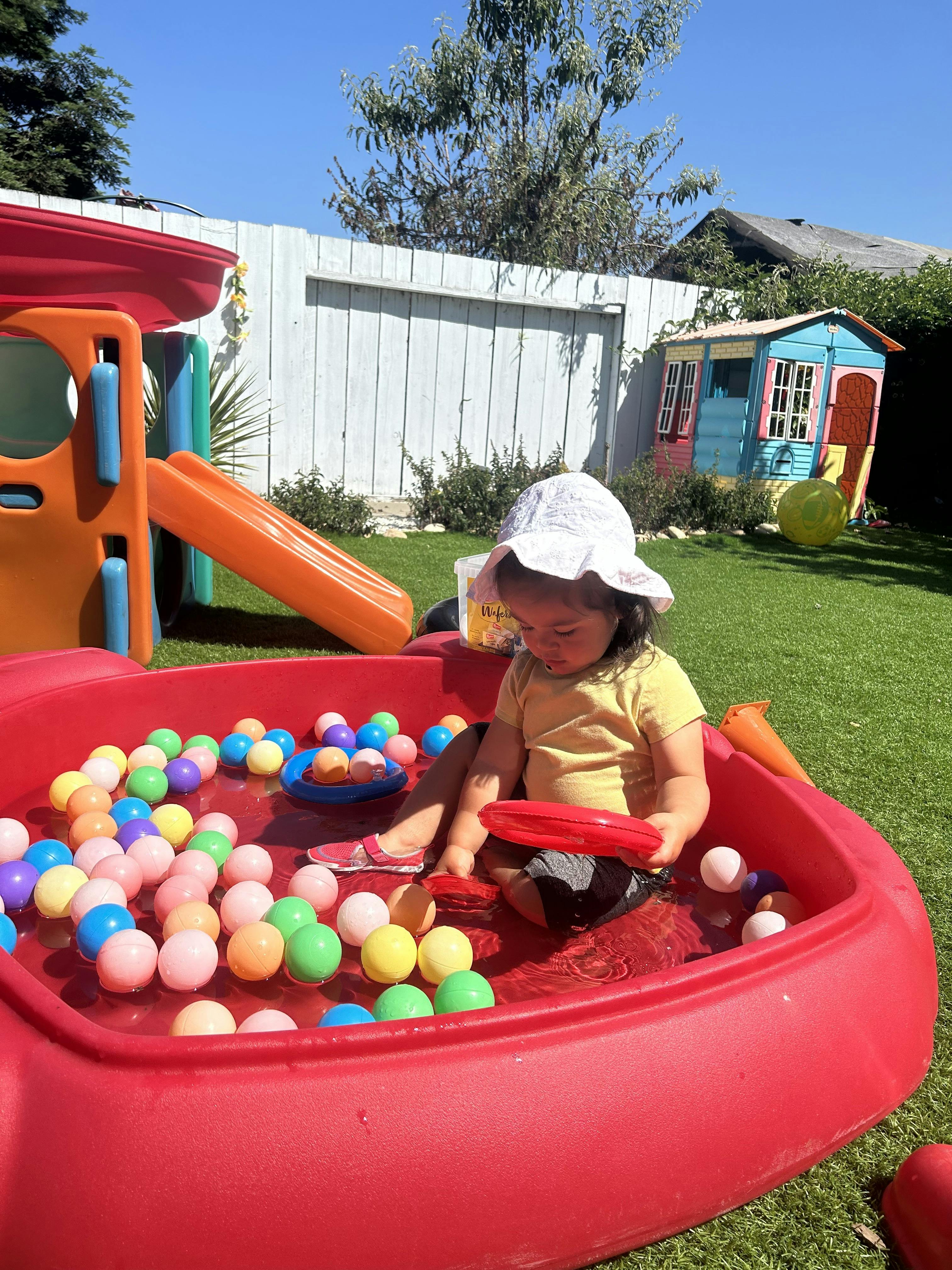 Child in a red plastic pool with colorful balls