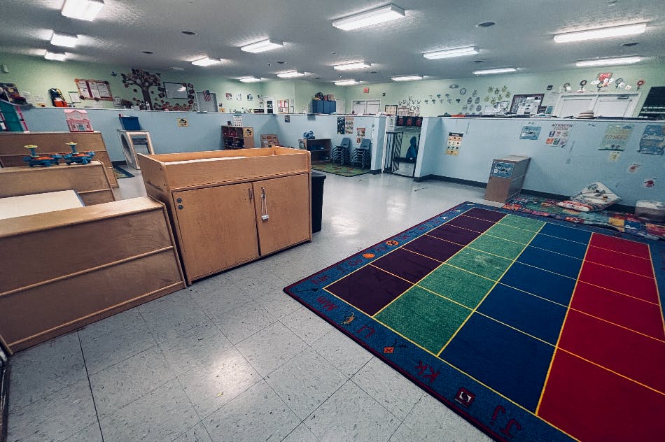 Empty preschool classroom with wooden furniture and a colorful alphabet rug
