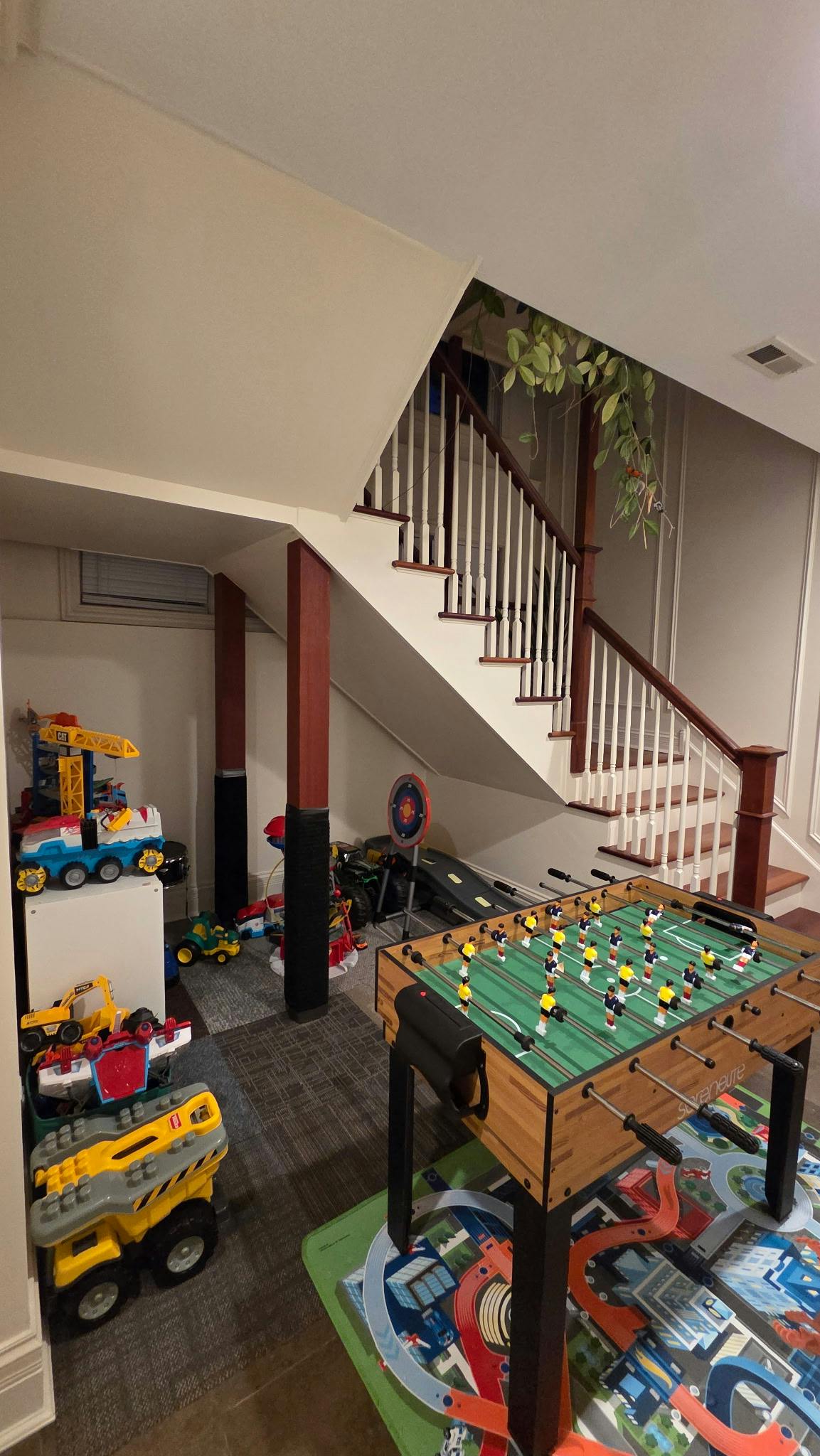 Foosball table and toys in a room with a staircase