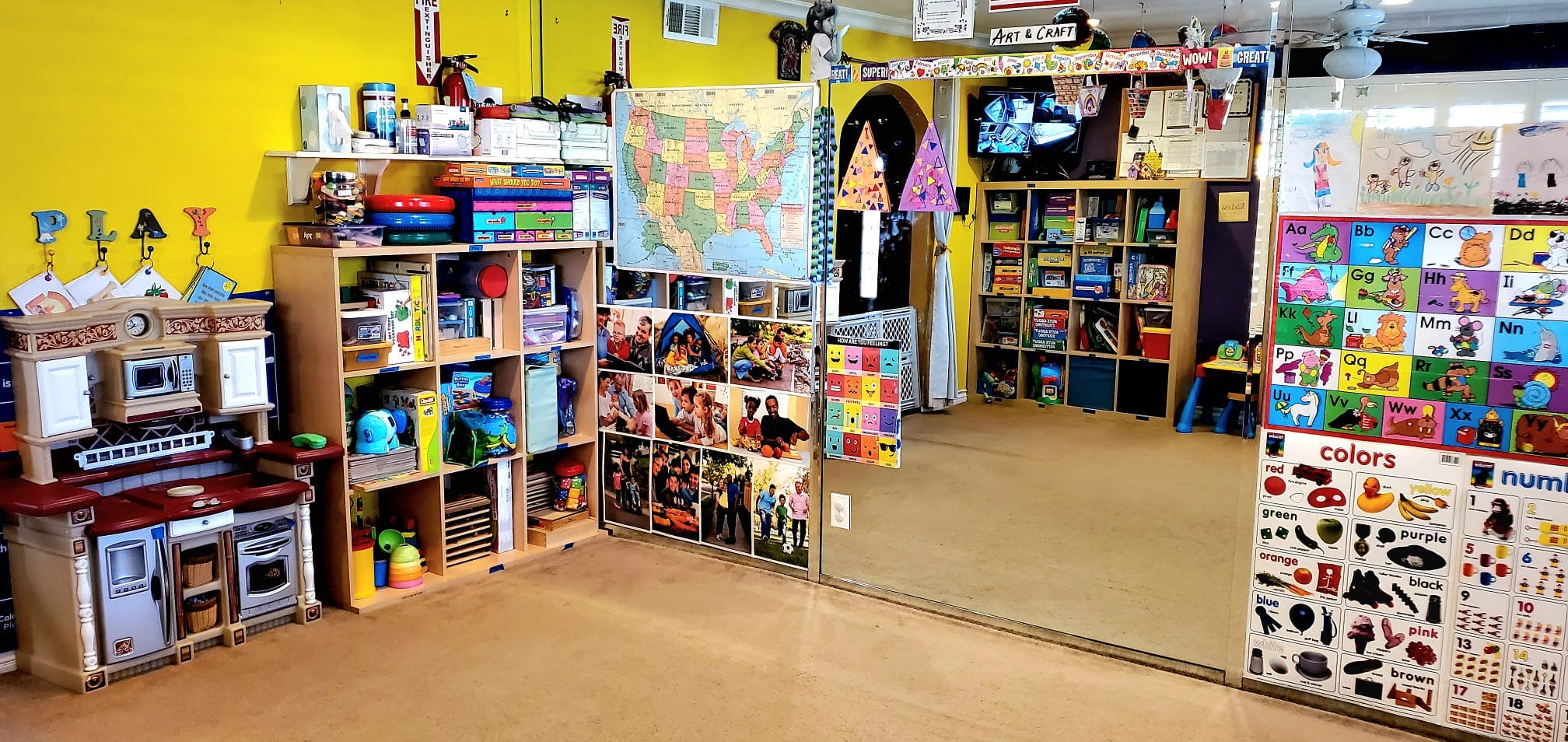 Playroom with shelves of toys and books, a play kitchen, and wall decorations