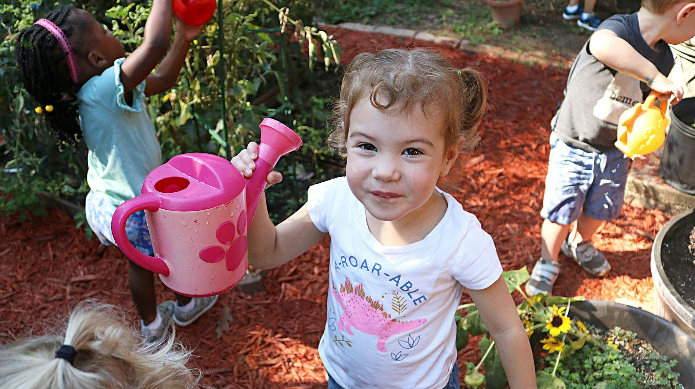 Child holding a pink watering can