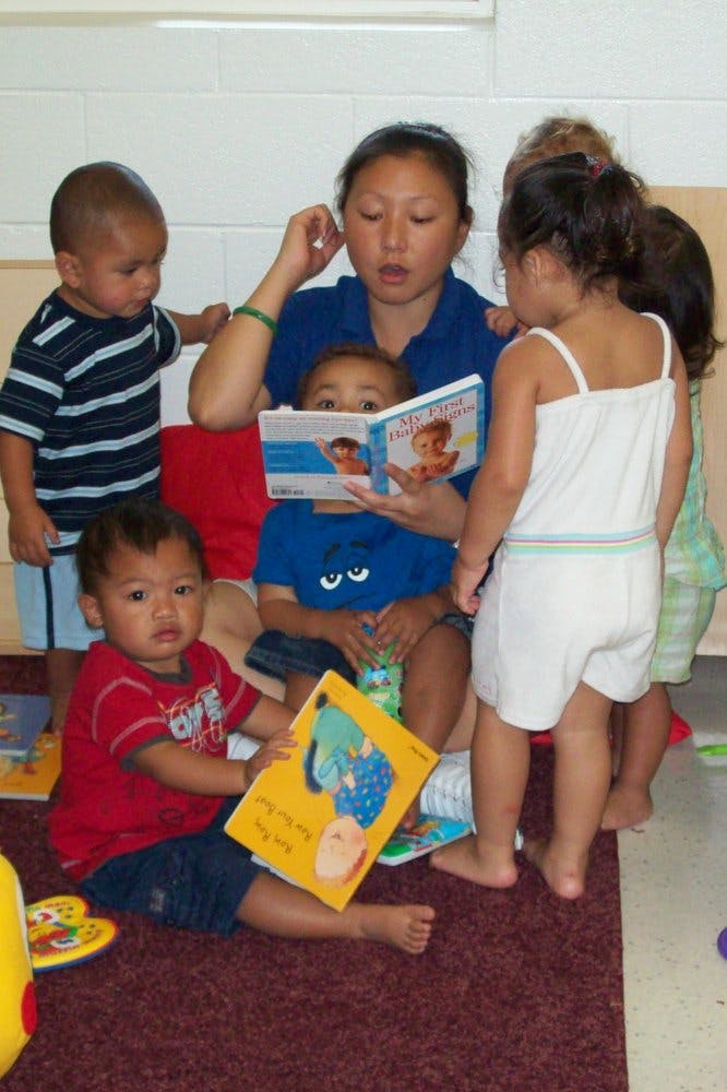 Adult person reading a book to several young children